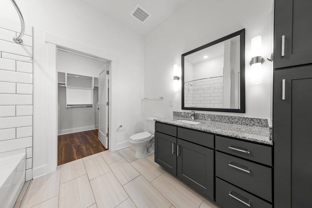 A bathroom with a toilet, sink, and a mirror.
