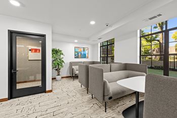A modern waiting room with grey couches and a black table.