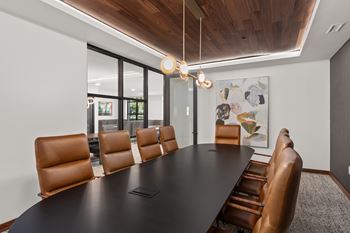 A conference room with a long table and brown leather chairs.