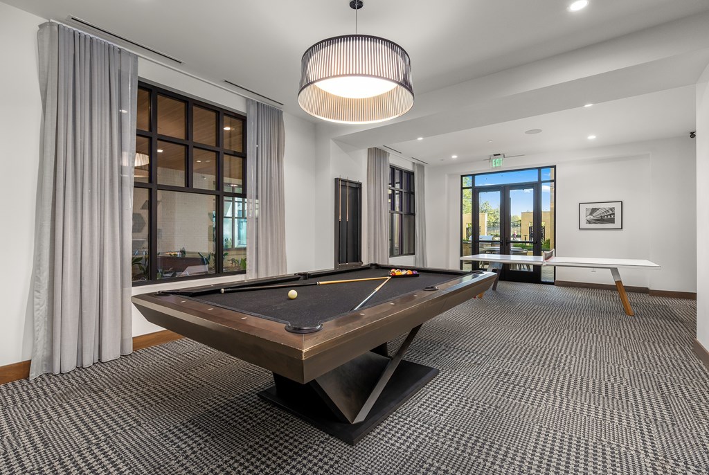 A pool table is in the middle of a room with a carpeted floor.