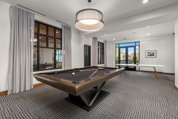 A pool table is in the middle of a room with a carpeted floor.