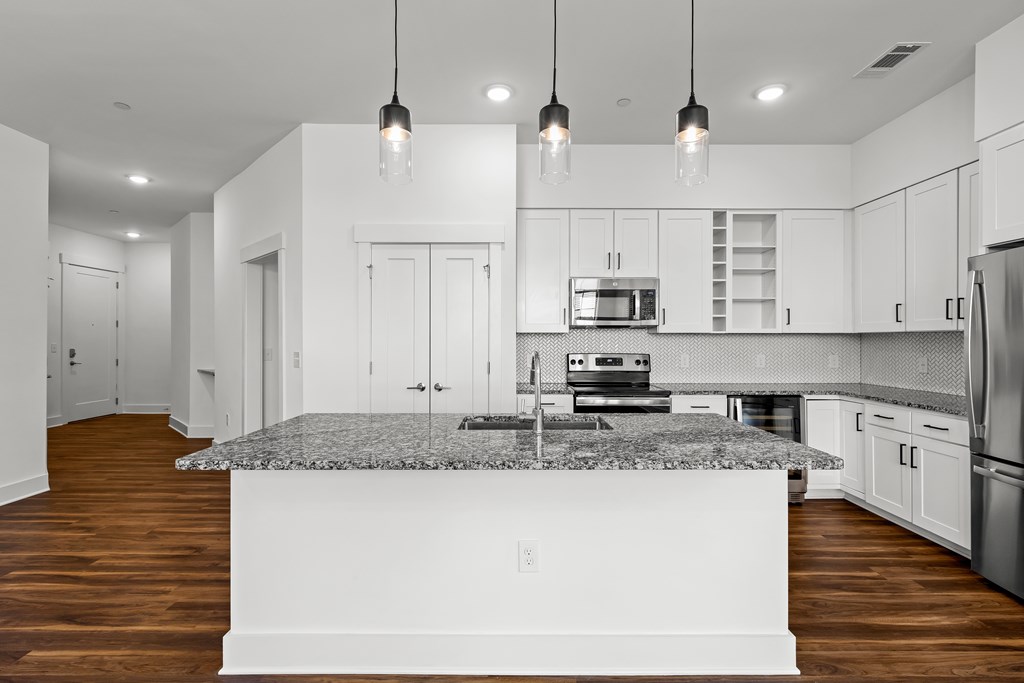A modern kitchen with a granite countertop and stainless steel appliances.