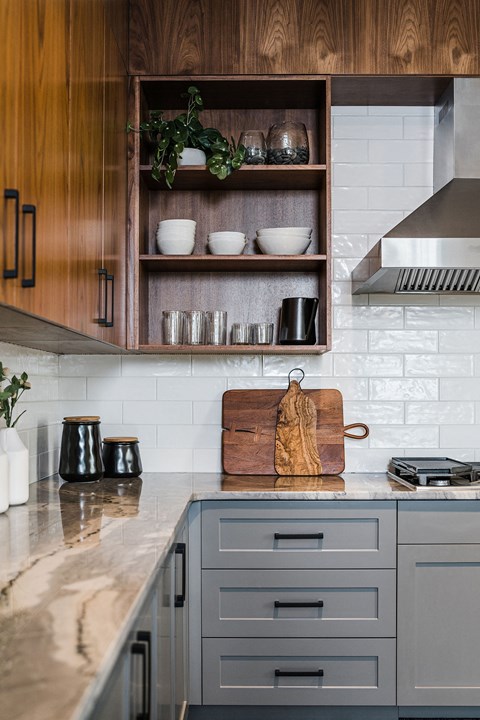 a kitchen with white tiles and wooden cabinets and a marble counter top