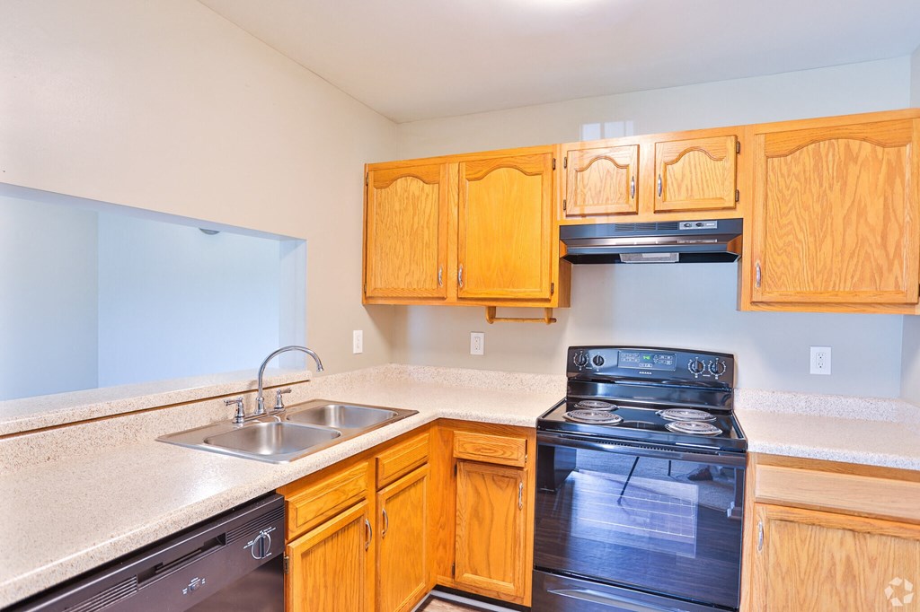 A kitchen with wooden cabinets and a black stove top oven.