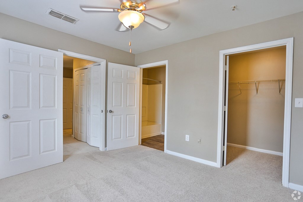 A room with a ceiling fan and four doors.