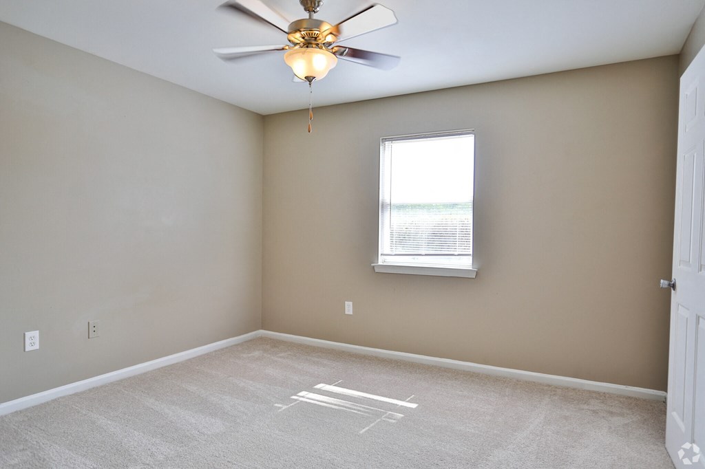 A room with a ceiling fan and a window.
