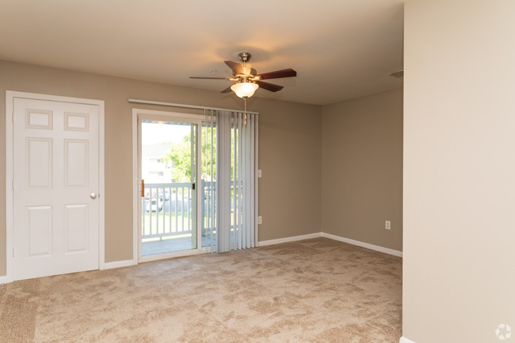 A room with a ceiling fan and sliding glass doors.