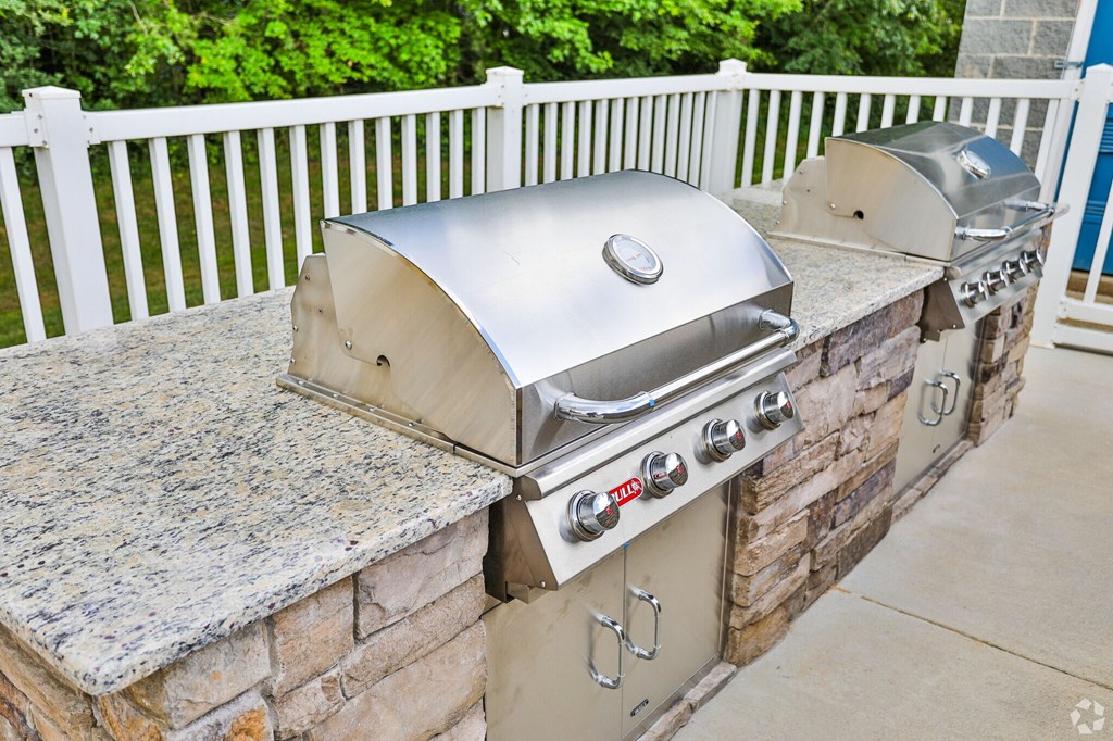 A silver BBQ grill on a stone and concrete patio.