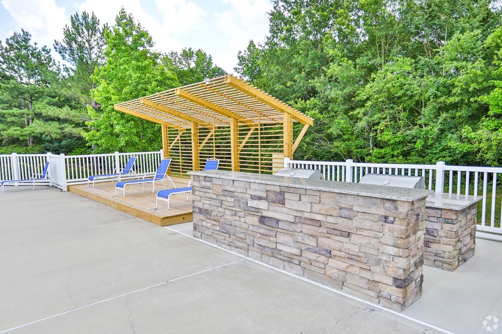 A wooden pavilion with a stone wall and two chairs.