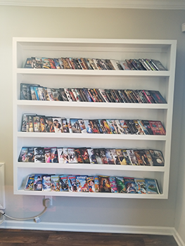 A white shelf with comic books on it.