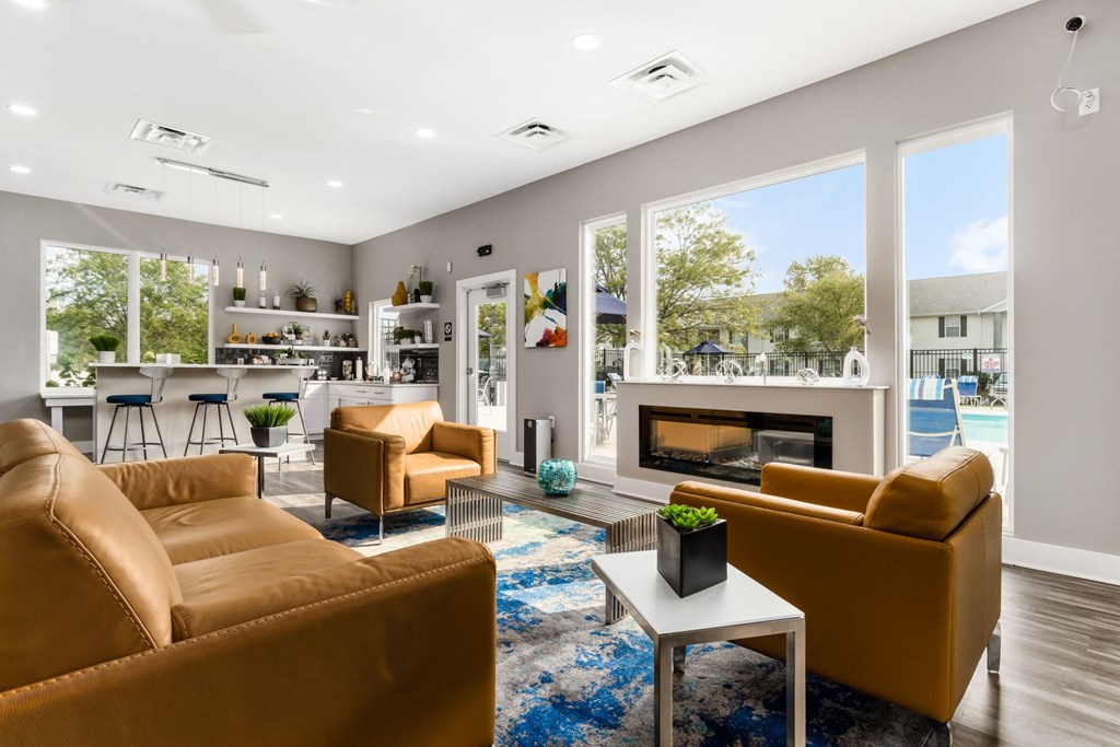 A living room with a fireplace and a view of a pool at Estates at Brentwood Lake Apartments, Reynoldsburg, OH, 43068