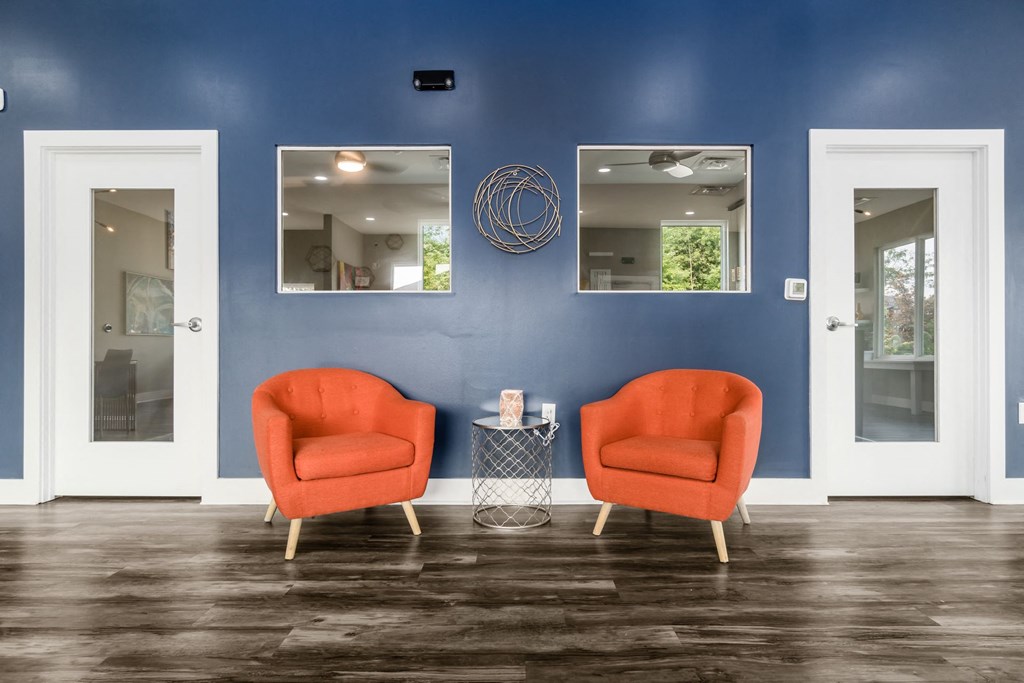 Two orange chairs sit in front of a wall with mirrors at Estates at Brentwood Lake Apartments, Ohio