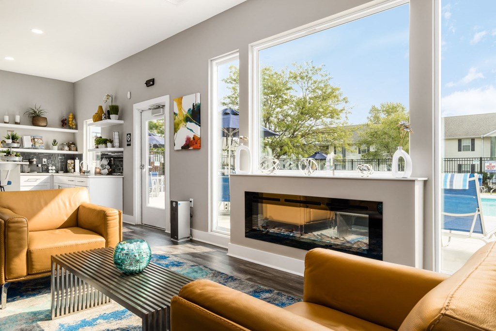 A modern living room with a fireplace and a view of the backyard at Estates at Brentwood Lake Apartments, Reynoldsburg, 43068