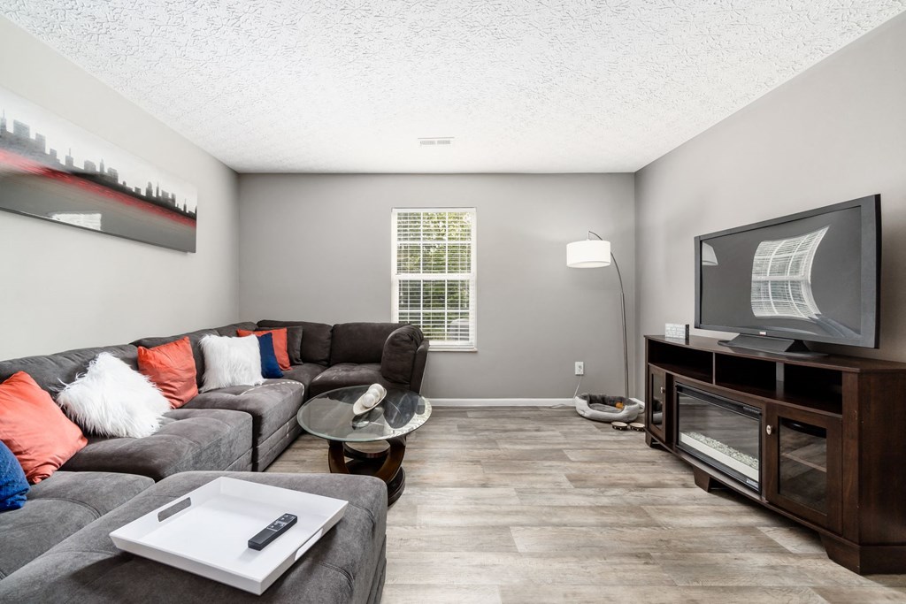 A living room with a grey couch and a television at Estates at Brentwood Lake Apartments, Ohio