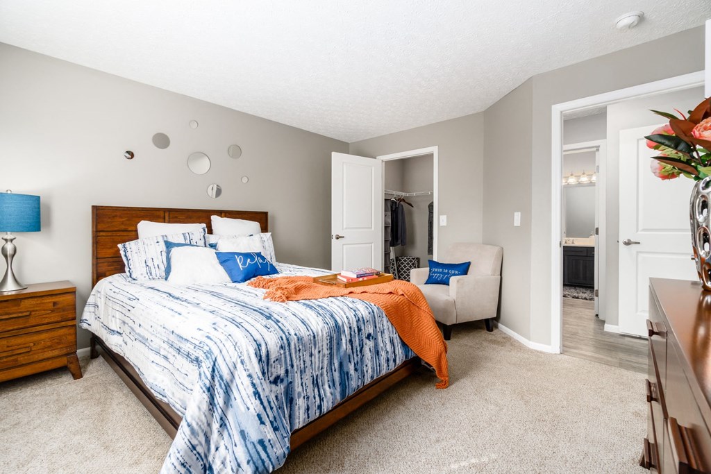 A bedroom with a bed, dresser, and chair at Estates at Brentwood Lake Apartments, Reynoldsburg, 43068