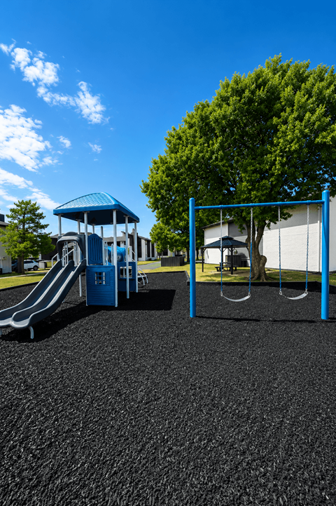 A playground with a blue slide and a blue and white swing set.