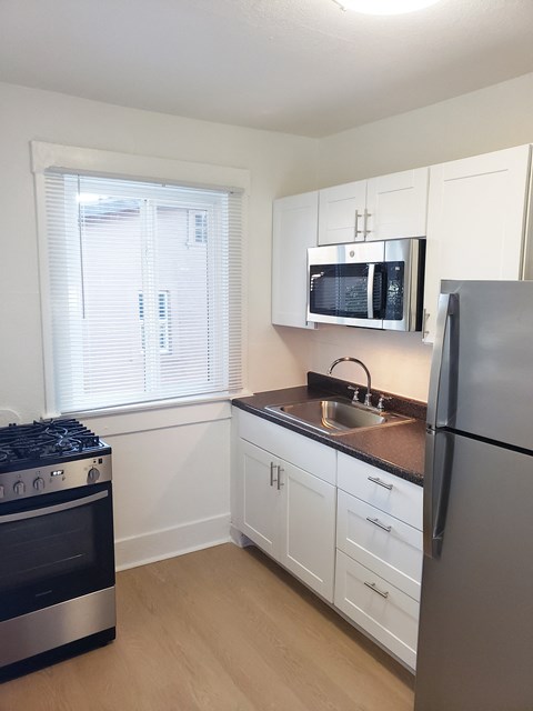 a kitchen with white cabinets and a sink and a refrigerator