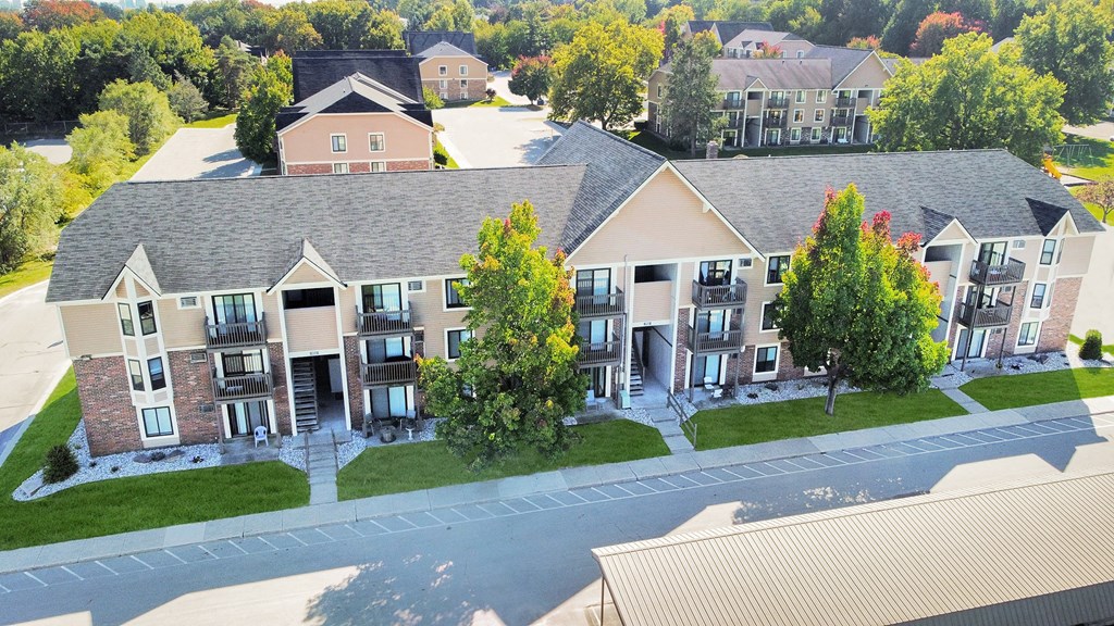 an aerial view of an apartment complex with green grass and trees