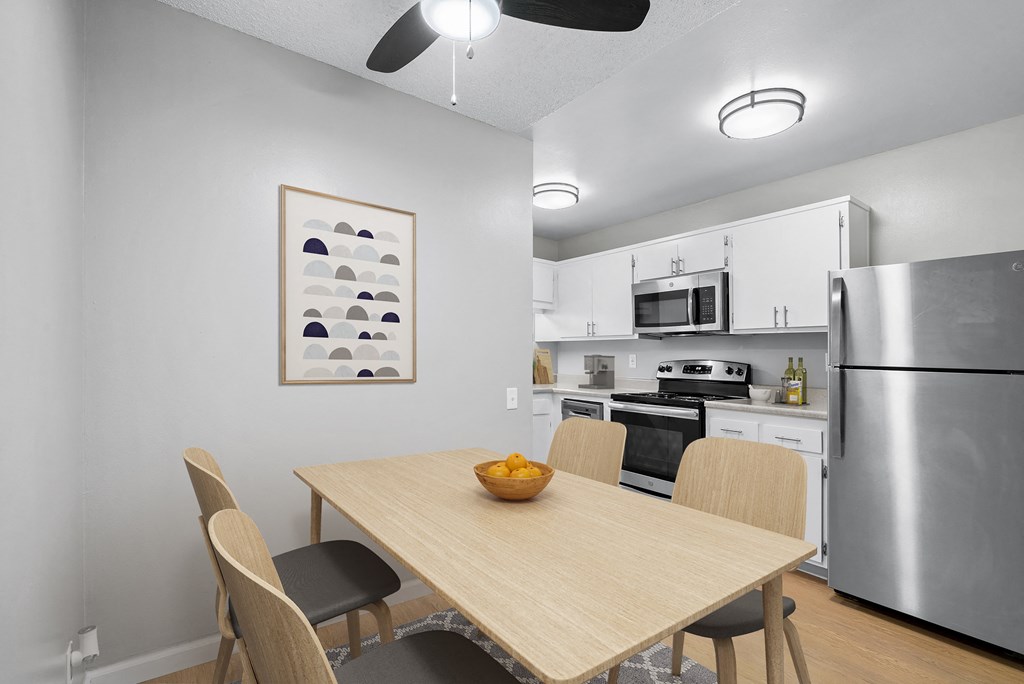 a dining room with a wooden table and chairs and a kitchen with stainless steel appliances