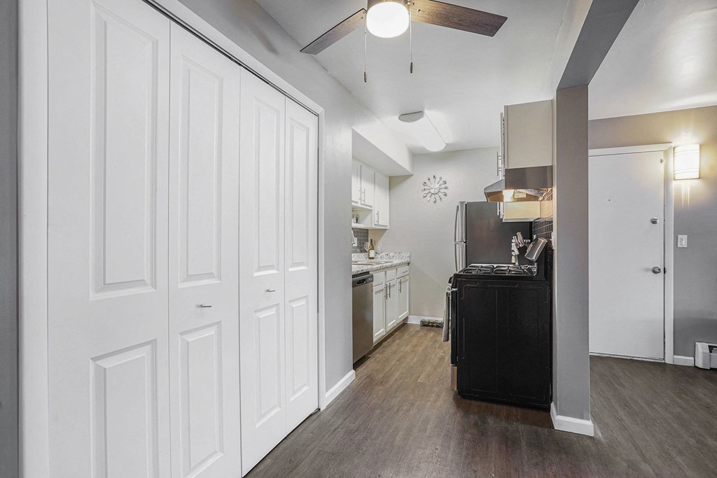 a kitchen with white walls and wood flooring and a black refrigerator and stove