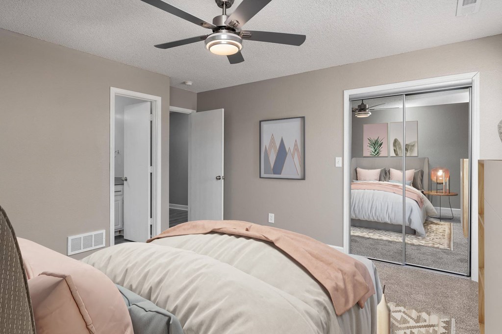 the bedroom of an apartment with two beds and a ceiling fan