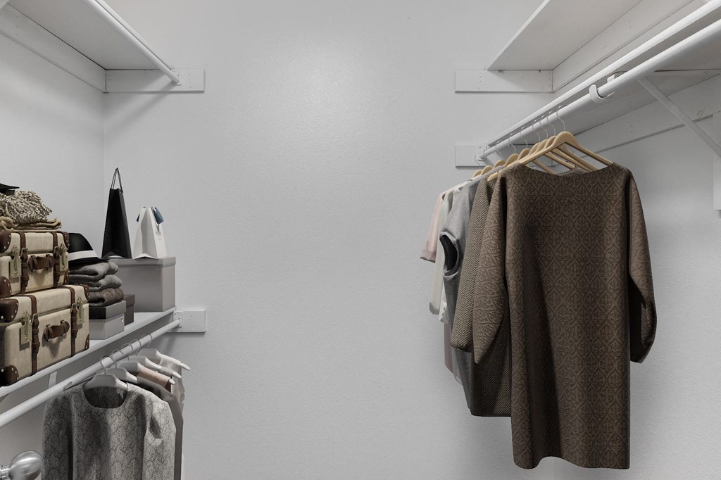 a walk in closet with clothes hanging on a rack
