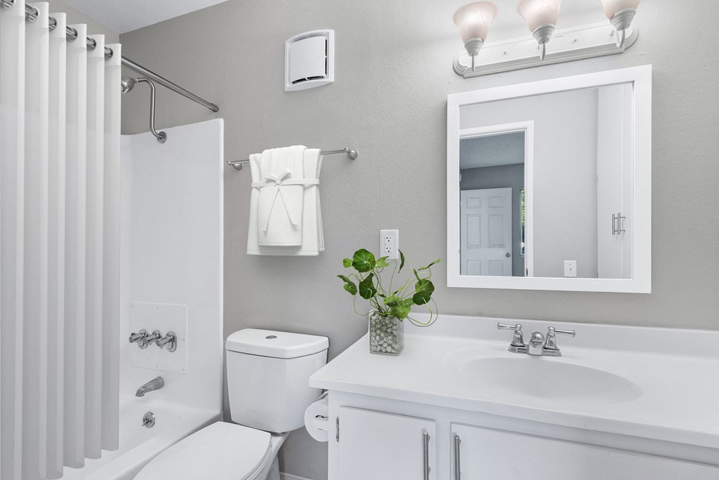 a white bathroom with a mirror and a toilet and a sink