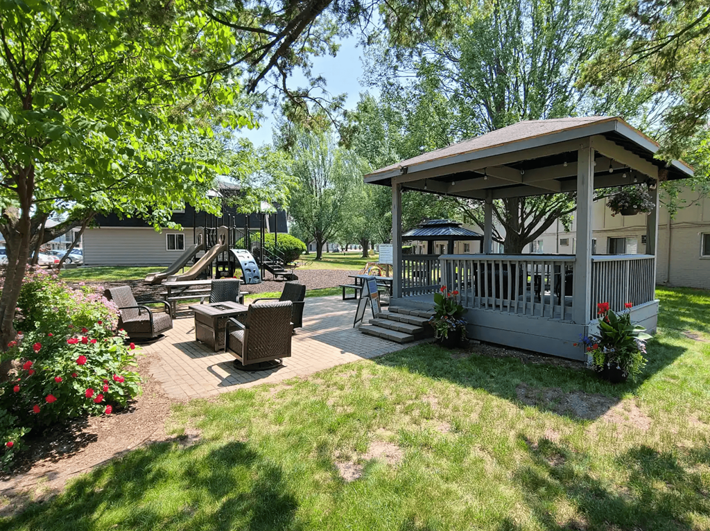 A gazebo is surrounded by a lawn and trees.