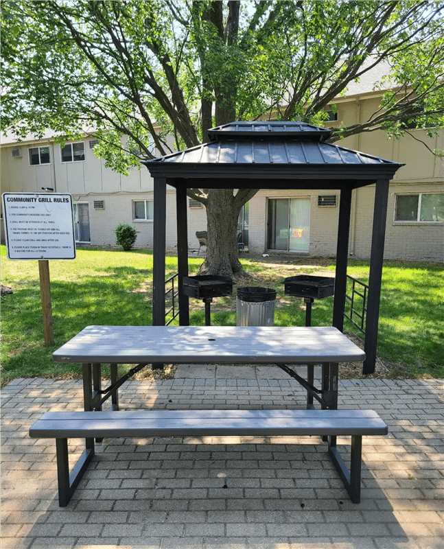 A gazebo with a canopy is surrounded by a brick patio and a sign that reads "Community Girls.".