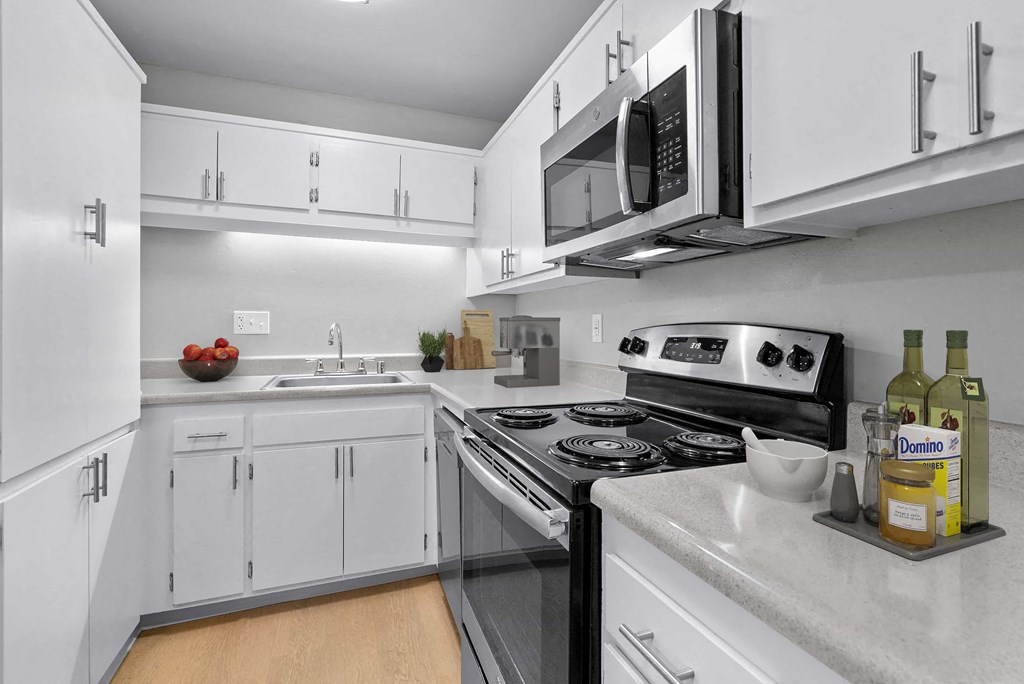 a kitchen with white cabinets and a stove and microwave