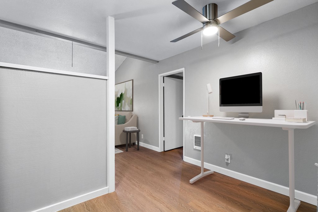 an open living room with a computer desk and a ceiling fan