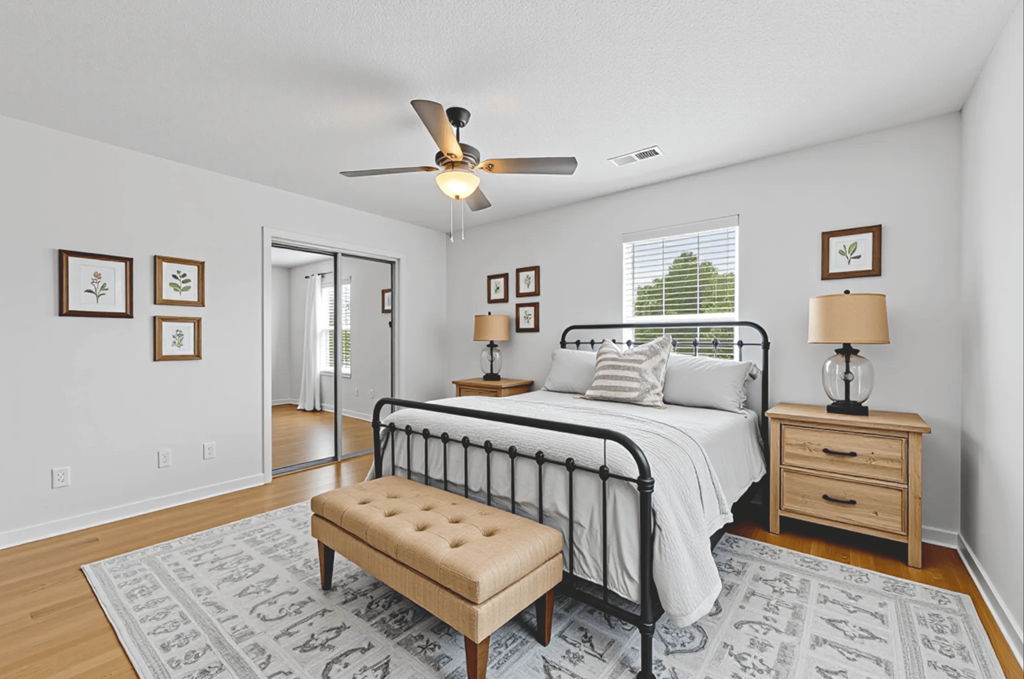 A bedroom with a bed, bench, and pictures on the wall.