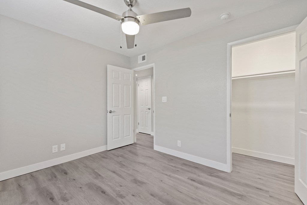an empty room with a ceiling fan and a door to a closet