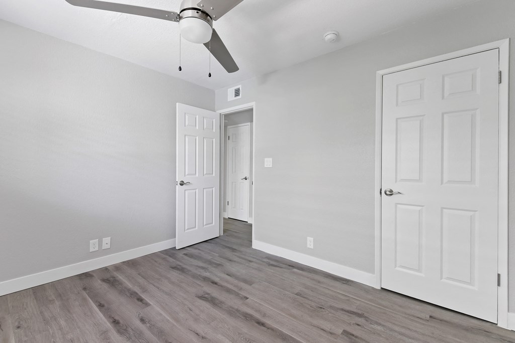 an empty room with white walls and a ceiling fan