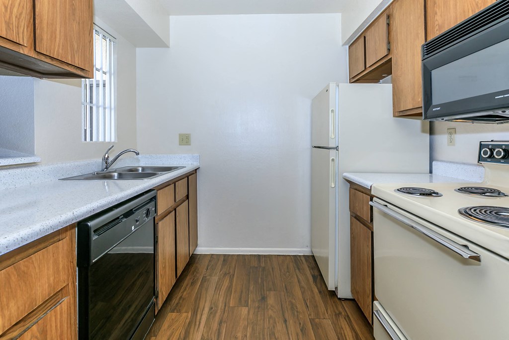 a kitchen with white appliances and wooden cabinets at Tides on Southern, Mesa, AZ