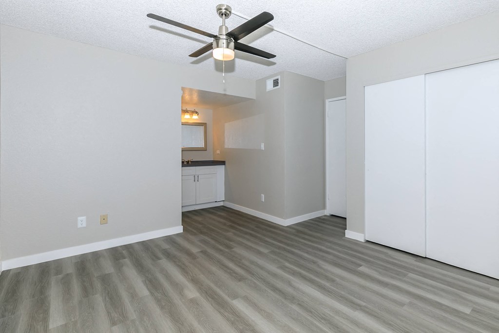an empty living room with a ceiling fan and a kitchen at Tides on Southern, Arizona