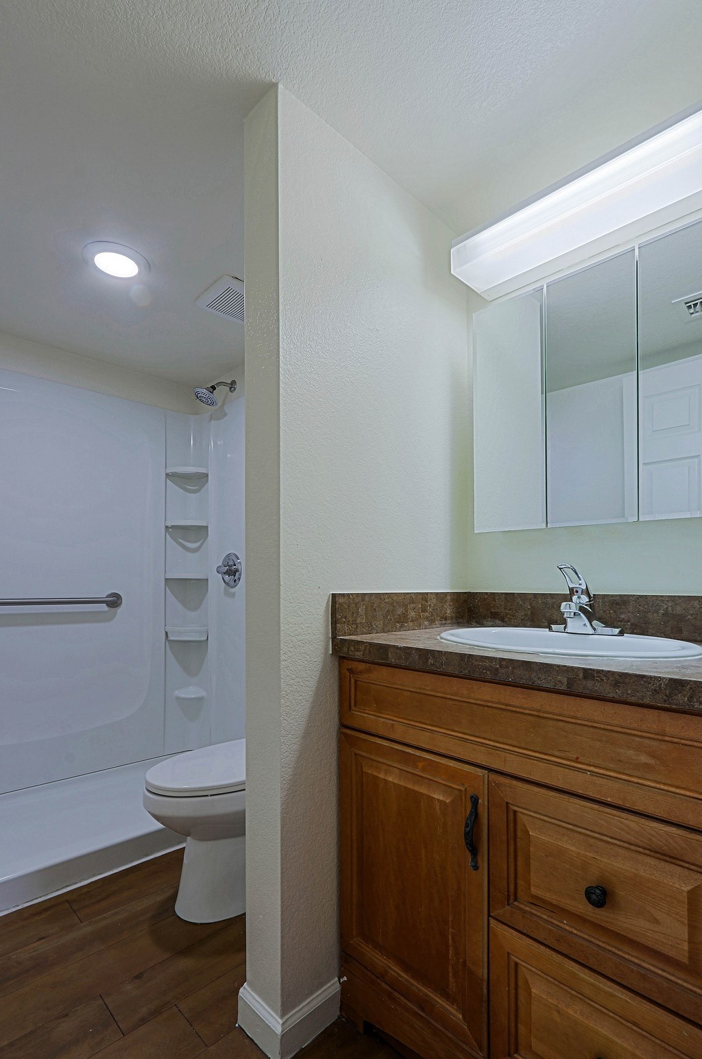 A bathroom with a toilet, sink, and wooden cabinet.