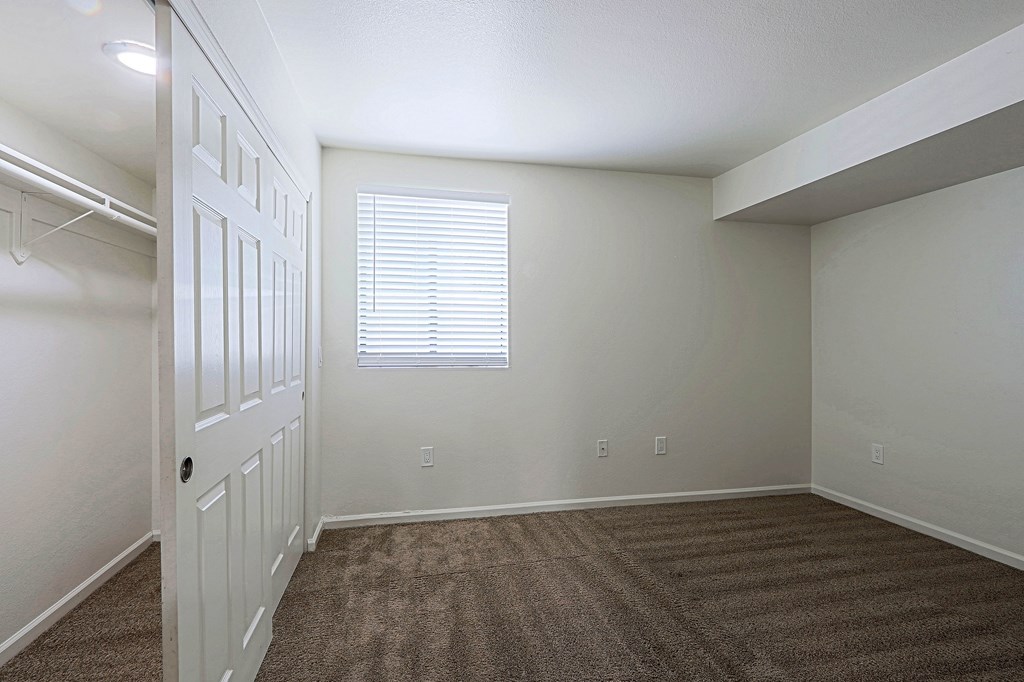 A room with a white door and a window with blinds.