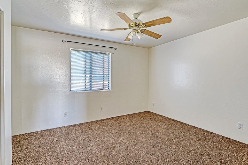 an empty room with a ceiling fan and a window
