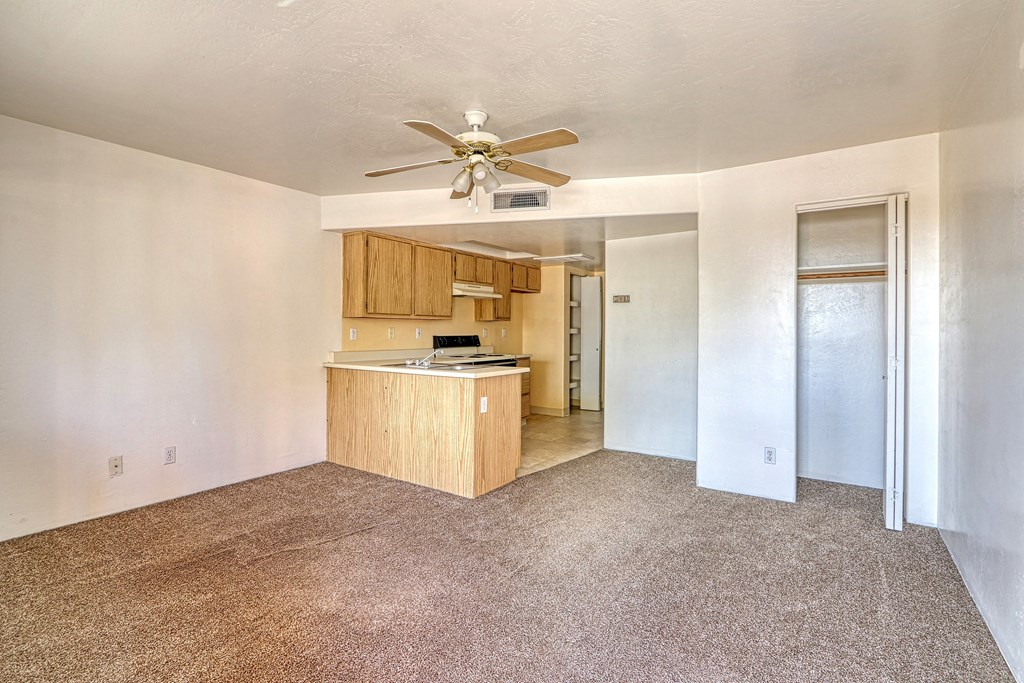 an empty living room and kitchen with a ceiling fan
