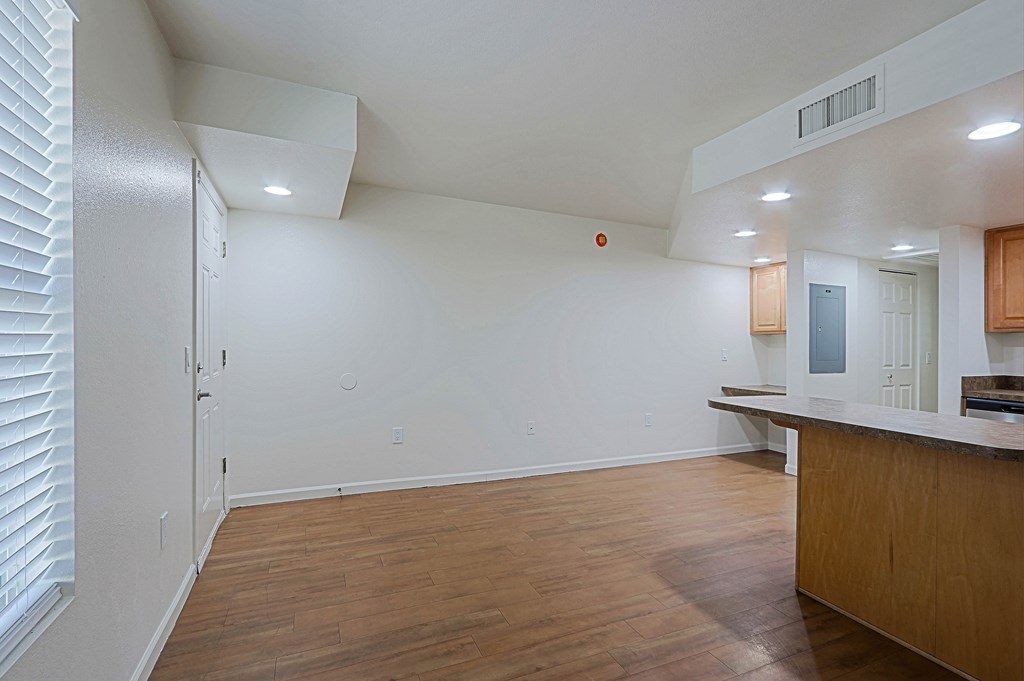 A room with a wooden floor and a white ceiling with a vent.