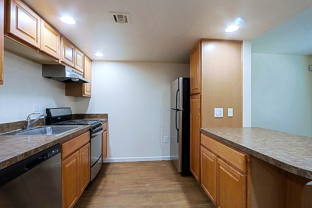 A kitchen with wooden cabinets and a black fridge.