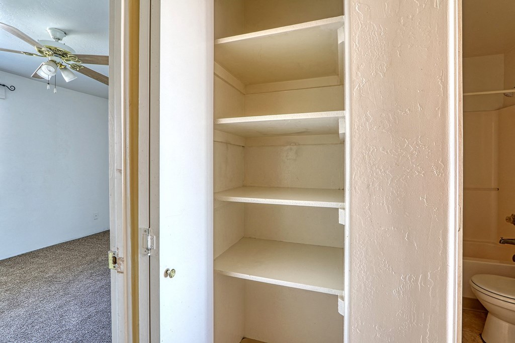 an empty closet in a bathroom with a ceiling fan
