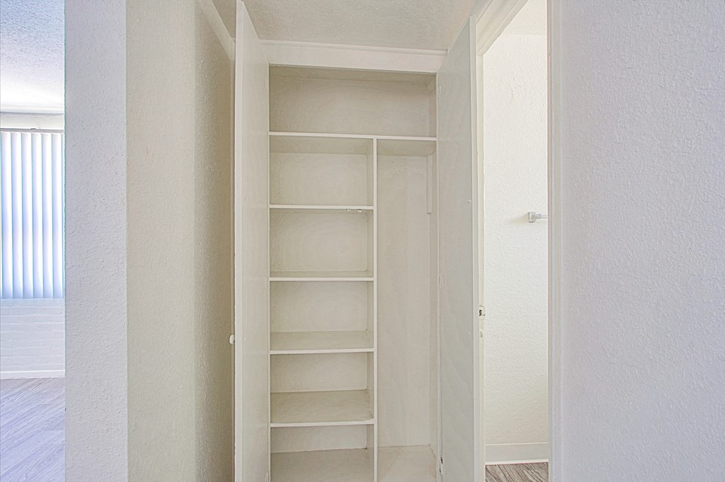 a walk in closet in a bedroom with white walls and white shelves