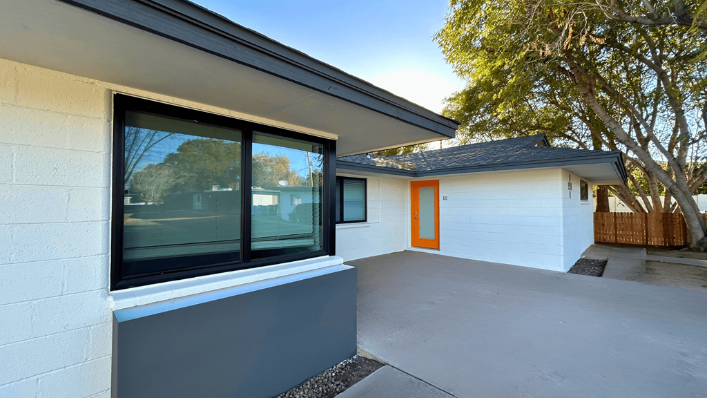the front patio of a white house with a large window