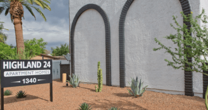 A sign for Highland 24 Apartment Home is in front of a white building.
