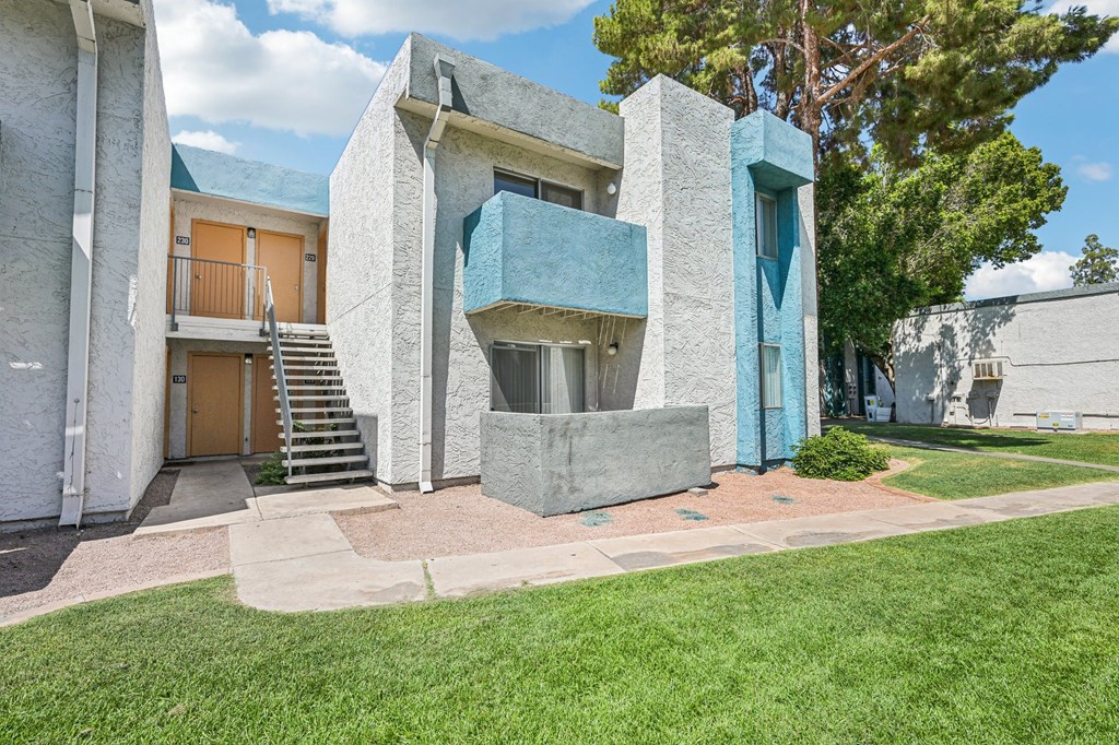 A modern building with a blue door and a green lawn in front.