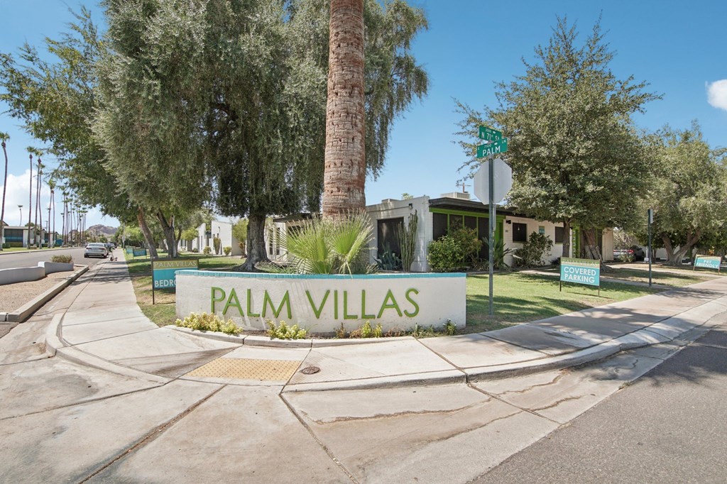 A sign that says Palm Villas in front of a tree.