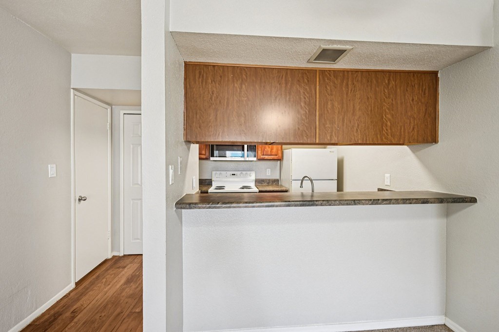 A kitchen with white walls and wooden cabinets.