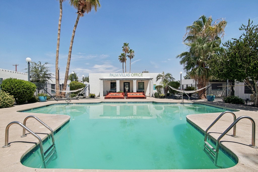 A pool with a diving board and a building in the background.